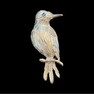 silver tone bird brooch with blue crystal eye.